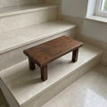 Taburete bajo rectangular de madera de alerce en acabado Nogal sobre escalones de piedra clara